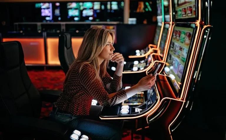 Woman sitting at a brightly lit slot machine in a casino, focused on the screen while holding a smartphone.