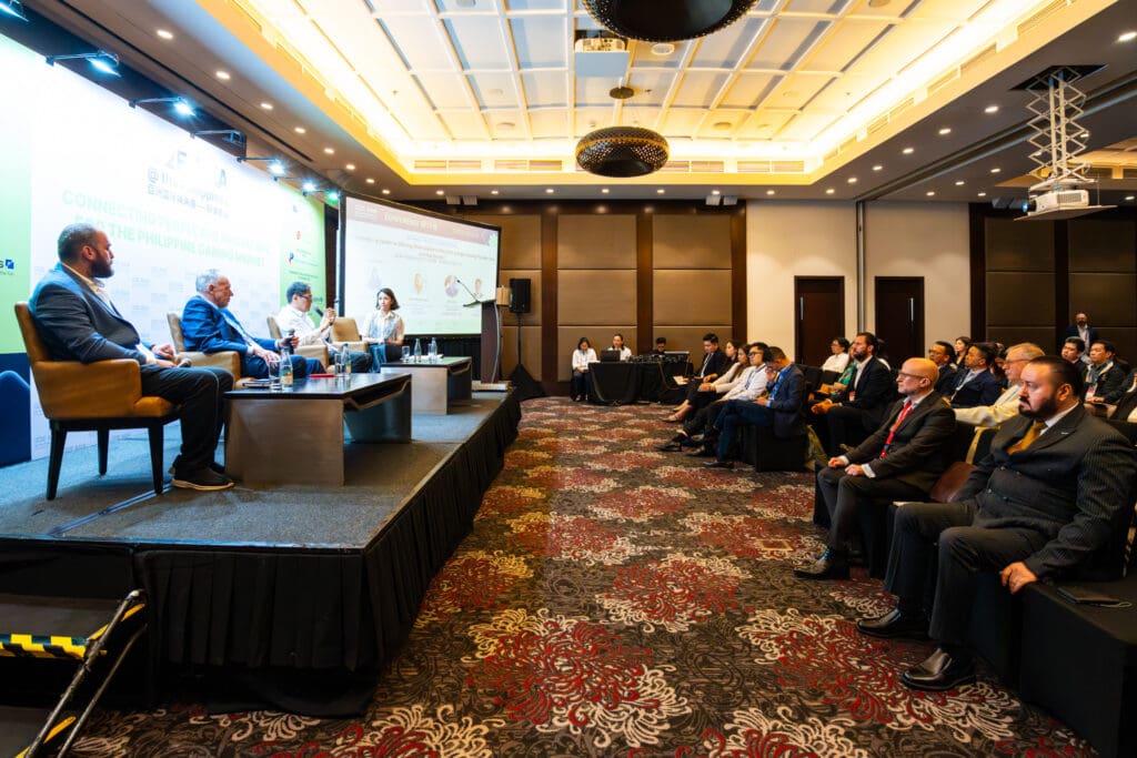 Panel discussion at the G2E Asia at the Philippines conference, with speakers seated on stage and attendees listening in a hotel conference room.