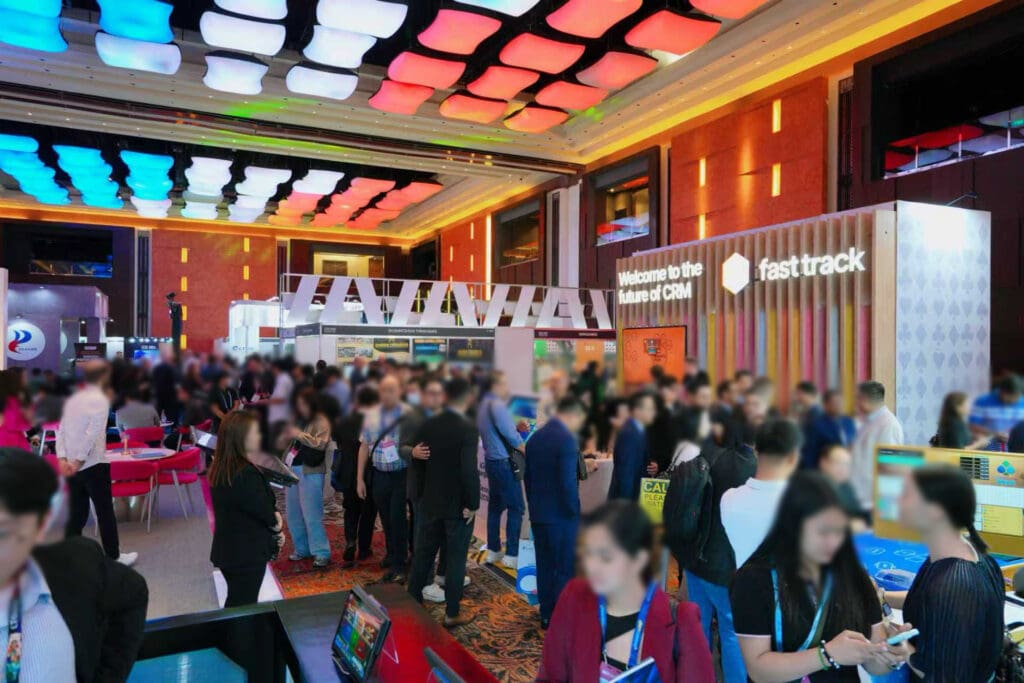 Crowded exhibition hall at G2E Asia at the Philippines, with attendees networking and visiting gaming and technology booths inside a brightly lit venue.