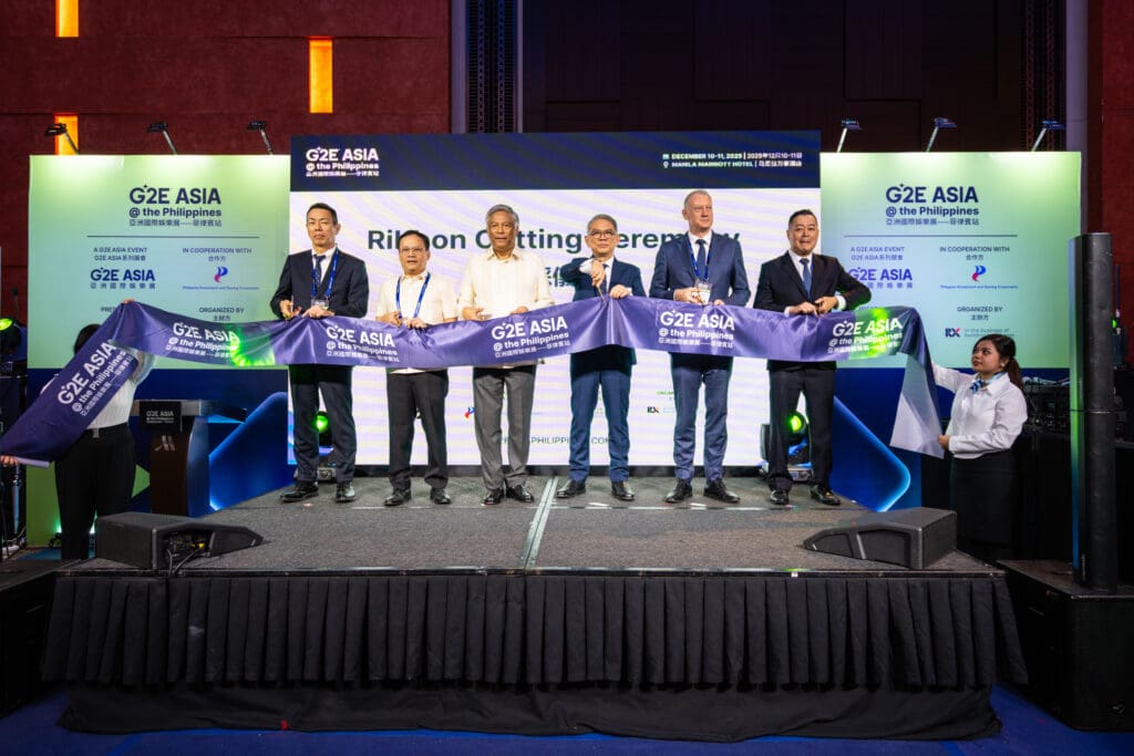 Officials and event leaders participate in the G2E Asia at the Philippines opening ceremony, holding a branded ribbon on stage before the ribbon-cutting.