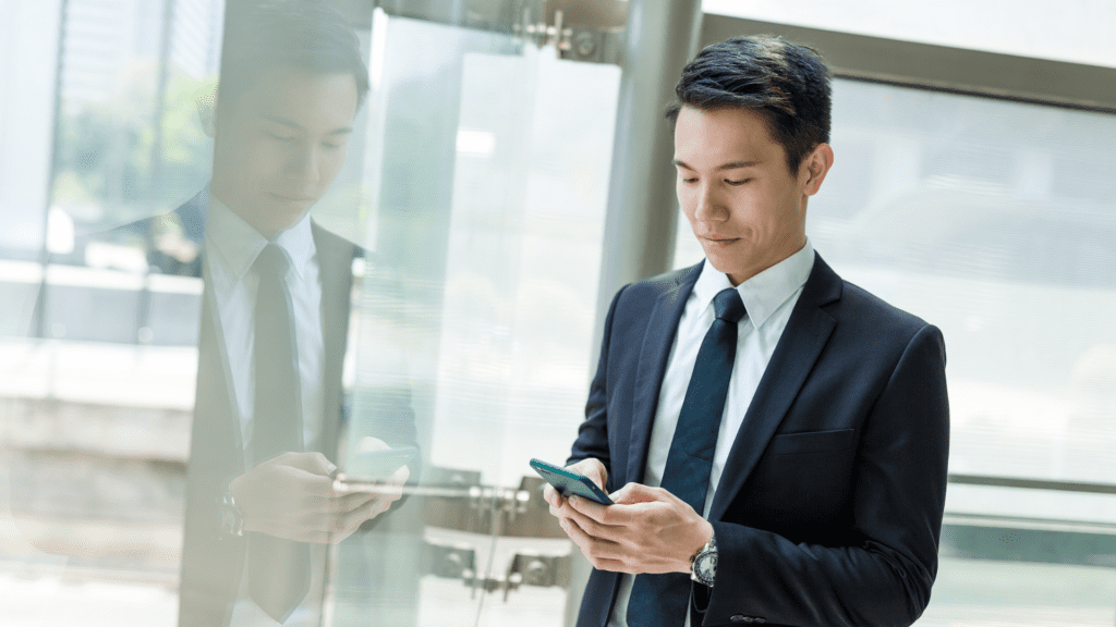Business professional in a suit using a smartphone in a modern office