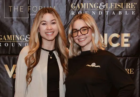 Talie and Katie smiling and posing together in front of a Gaming & Leisure Roundtable backdrop at The Forum 2026.