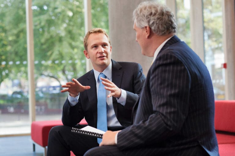 Two business professionals engaged in a one-on-one conversation in an office setting.